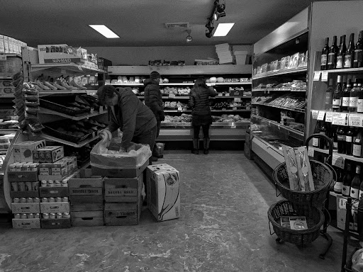 An essential worker stacking the shelves as shoppers lurk through the aisles.