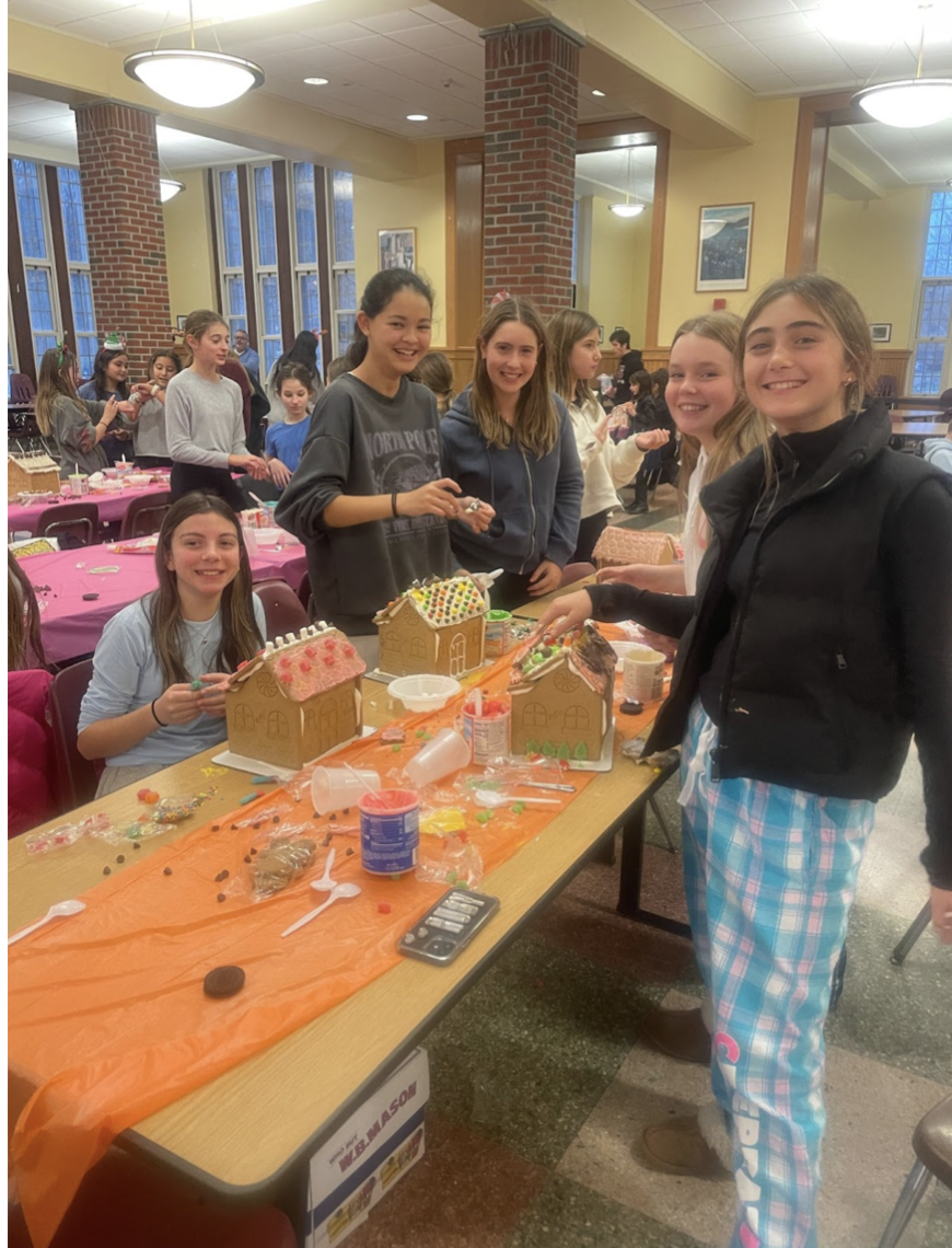 Middle schoolers pose with their gingerbread houses halfway through making.