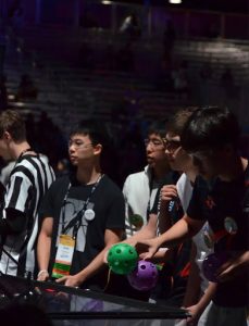 Team captains Kevin Han '26 (left) and Nathan Tao '26 (center) preparing game pieces before the start of their match