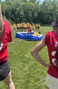 Four teams participate in "Steal the Bacon," a game in which they must rush to the center and grab a specific object from the kiddie pool.
